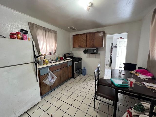 kitchen featuring sink, stainless steel gas range, and white fridge