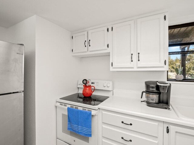 kitchen featuring white cabinetry, stainless steel refrigerator, and white range with electric cooktop