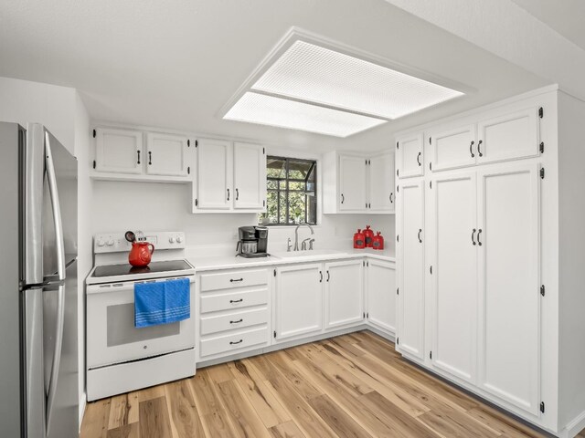 kitchen with white cabinets, sink, stainless steel fridge, and white range with electric stovetop