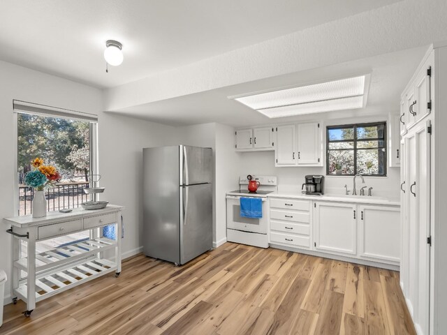 kitchen with white electric range, sink, white cabinetry, light wood-type flooring, and stainless steel fridge