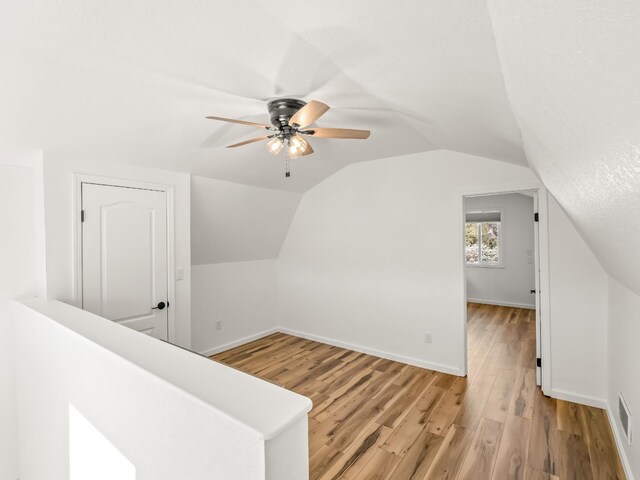 additional living space with vaulted ceiling, ceiling fan, and light wood-type flooring