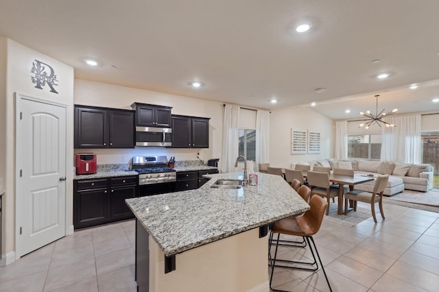 kitchen with a breakfast bar, sink, a kitchen island with sink, light tile patterned floors, and stainless steel appliances