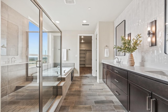 bathroom with decorative backsplash, vanity, plus walk in shower, and tile walls