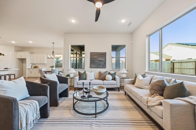 living room with ceiling fan with notable chandelier