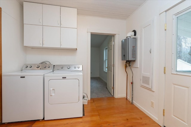 laundry room featuring water heater, washer and dryer, cabinets, and light hardwood / wood-style flooring