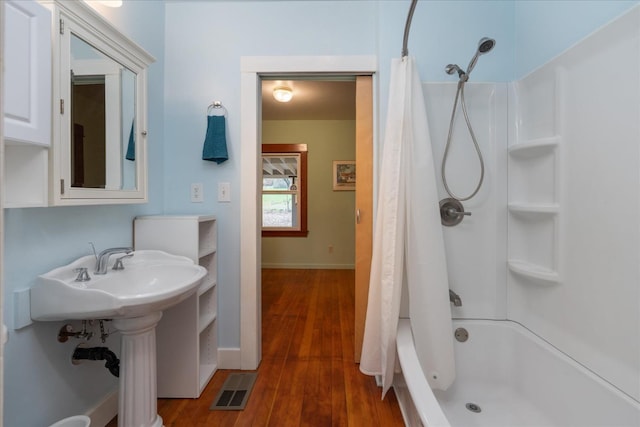 bathroom featuring hardwood / wood-style flooring, shower / tub combo with curtain, and sink