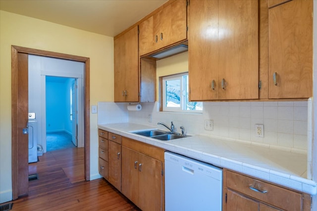 kitchen with sink, dark wood-type flooring, dishwasher, tasteful backsplash, and tile countertops