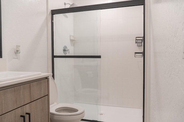 bathroom with walk in shower, vanity, and toilet