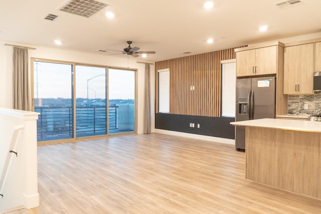 kitchen featuring light hardwood / wood-style flooring, ceiling fan, appliances with stainless steel finishes, backsplash, and light brown cabinets