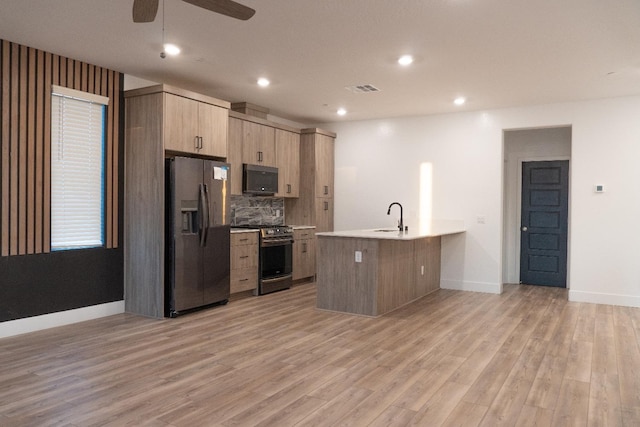 kitchen with sink, light brown cabinets, light hardwood / wood-style floors, and appliances with stainless steel finishes