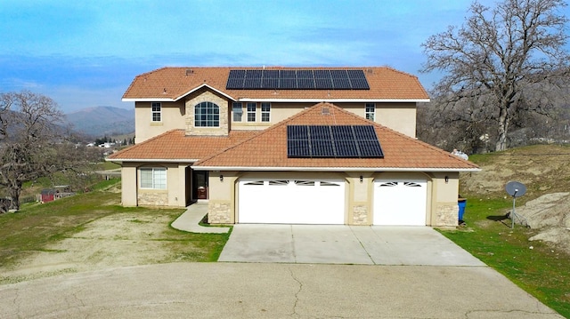 view of front of home featuring a garage, a mountain view, a front lawn, and solar panels