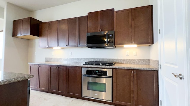 kitchen with appliances with stainless steel finishes, light stone countertops, and dark brown cabinets