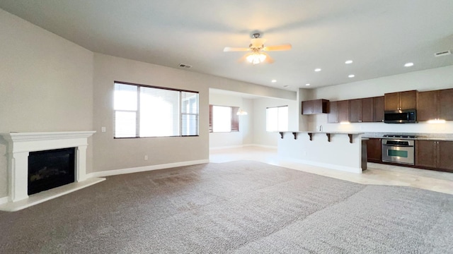 unfurnished living room with ceiling fan and light carpet