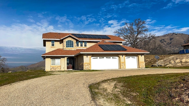 view of front of house with a mountain view, a garage, and solar panels