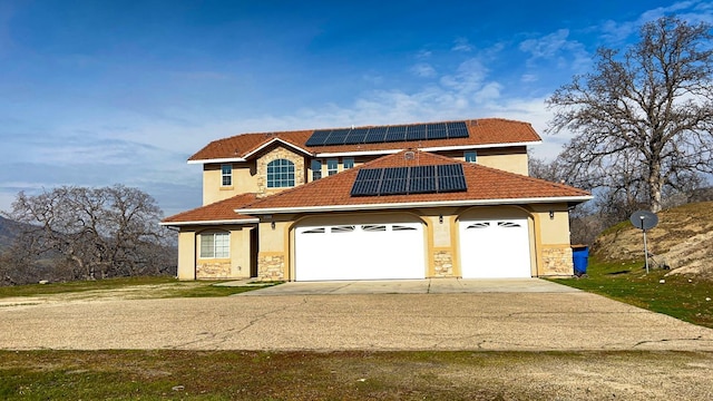 mediterranean / spanish-style house featuring a garage and solar panels