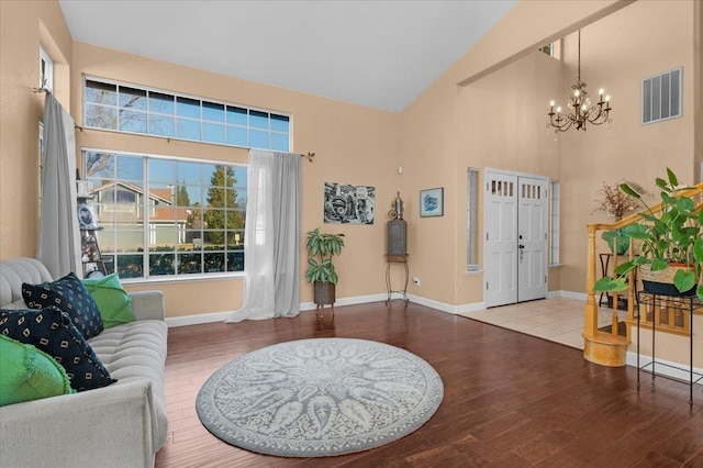 entrance foyer featuring hardwood / wood-style flooring, high vaulted ceiling, and an inviting chandelier