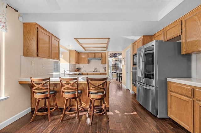 kitchen featuring tasteful backsplash, dark hardwood / wood-style floors, a kitchen bar, and black appliances