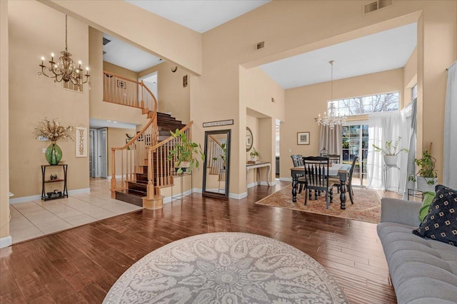 living room with light wood-type flooring, a high ceiling, and a notable chandelier