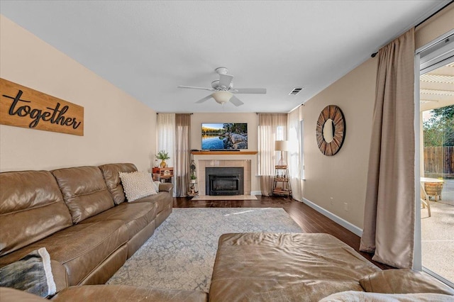 living room with a tile fireplace, dark hardwood / wood-style floors, and ceiling fan