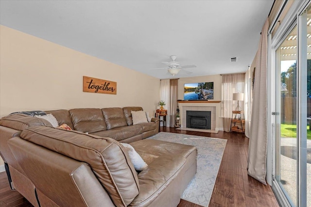 living room featuring dark hardwood / wood-style flooring, a tile fireplace, and ceiling fan