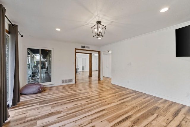 spare room featuring ornamental molding, light hardwood / wood-style flooring, and a notable chandelier