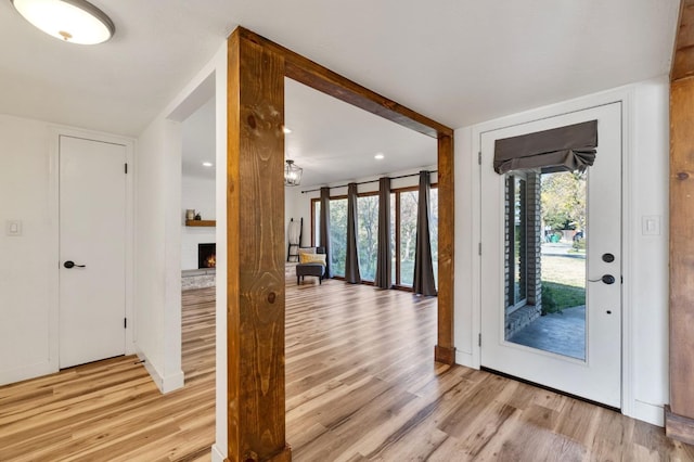 foyer entrance with a fireplace, plenty of natural light, and light wood-type flooring