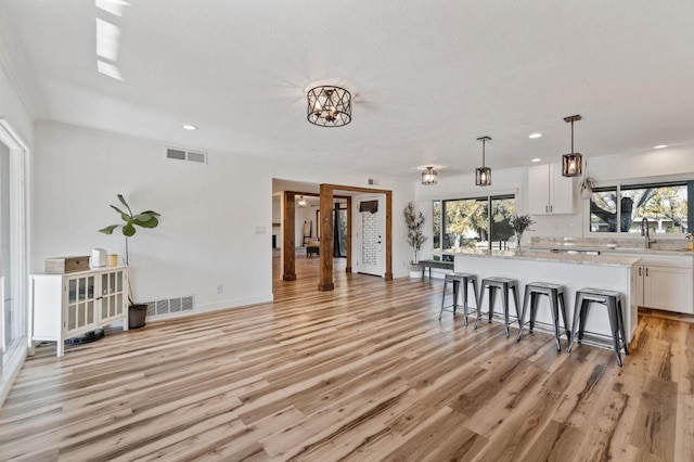 kitchen with white cabinetry, a kitchen breakfast bar, a center island, and decorative light fixtures