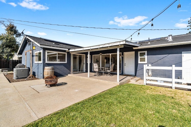 back of house featuring cooling unit, a lawn, a patio, and an outdoor fire pit