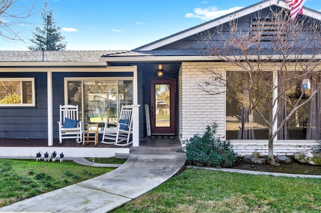 doorway to property with covered porch and a lawn