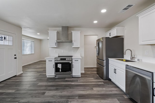 kitchen with sink, dark wood-type flooring, stainless steel appliances, white cabinets, and wall chimney exhaust hood