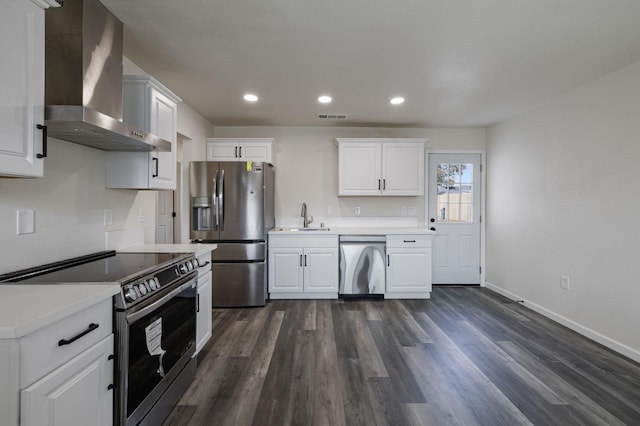 kitchen with white cabinetry, appliances with stainless steel finishes, sink, and wall chimney range hood