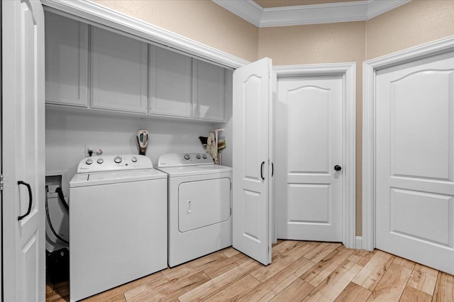 laundry room featuring light hardwood / wood-style floors, crown molding, washing machine and dryer, and cabinets