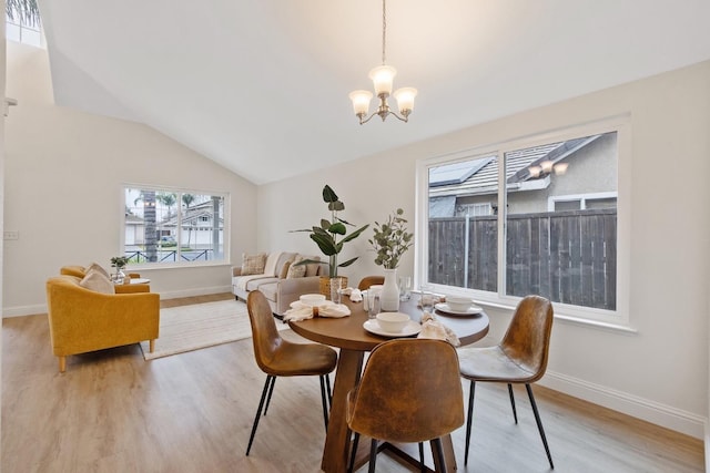 dining area with a notable chandelier, vaulted ceiling, and light wood-type flooring