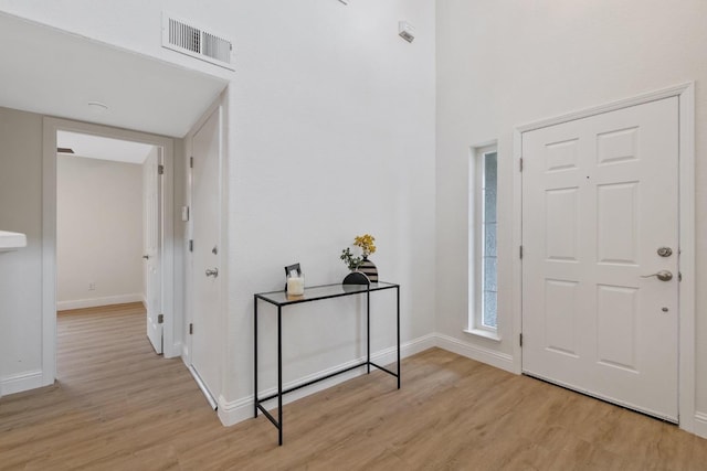 entryway featuring a towering ceiling and light hardwood / wood-style floors