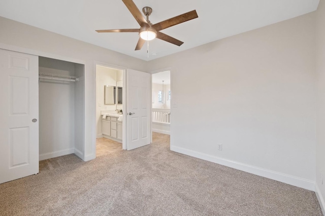 unfurnished bedroom with sink, ceiling fan, ensuite bathroom, light colored carpet, and a closet