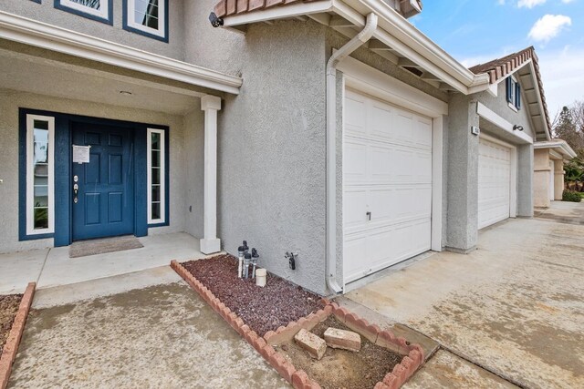 968 E Muncie, Fresno, CA 93720 - doorway to property with driveway, stucco siding, a tiled roof, and a garage