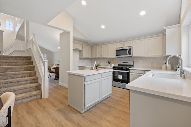 kitchen featuring sink, vaulted ceiling, appliances with stainless steel finishes, light hardwood / wood-style floors, and backsplash