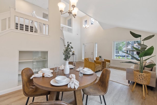 dining space with high vaulted ceiling, a chandelier, and light hardwood / wood-style floors