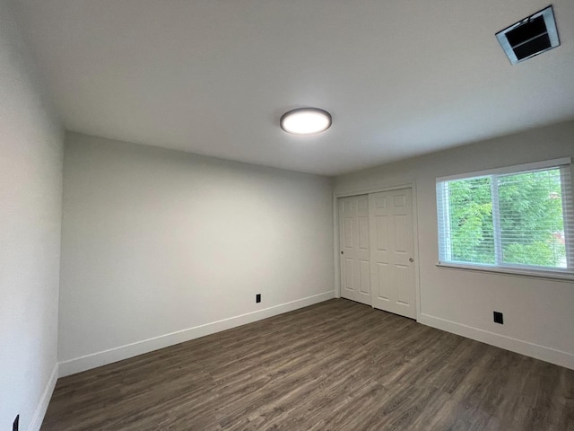 unfurnished bedroom featuring dark wood-type flooring and a closet