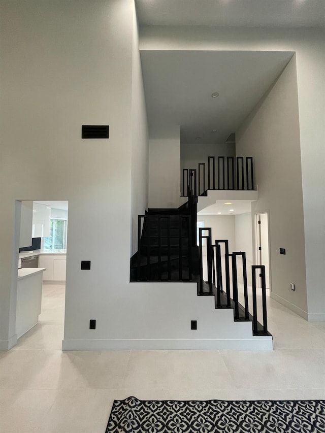 stairway featuring a towering ceiling