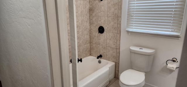 bathroom featuring tiled shower / bath combo and toilet