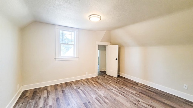 bonus room with hardwood / wood-style flooring, vaulted ceiling, and a textured ceiling