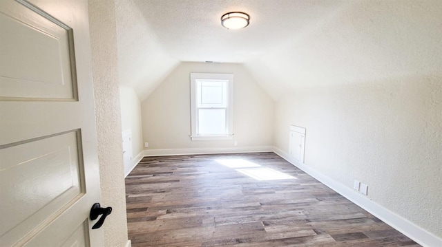 bonus room featuring dark wood-type flooring, vaulted ceiling, and a textured ceiling