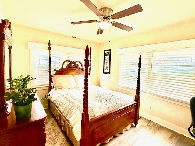 bedroom with ceiling fan, light hardwood / wood-style floors, and multiple windows