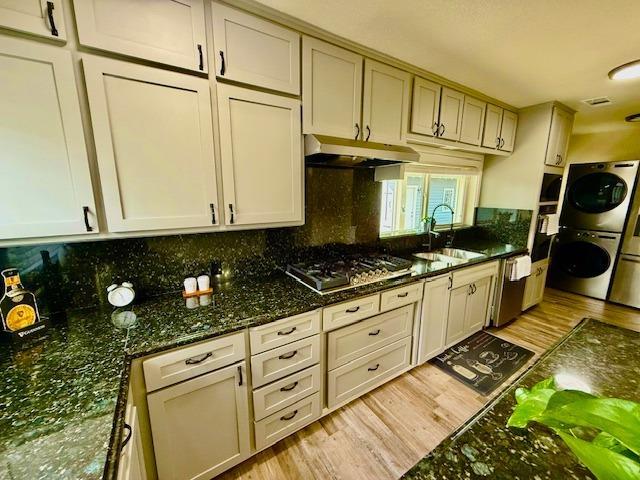 438 E Clinton Ave, Fresno, CA 93704 - kitchen with a sink, estacked washer and dryer, stainless steel appliances, under cabinet range hood, and light wood finished floors