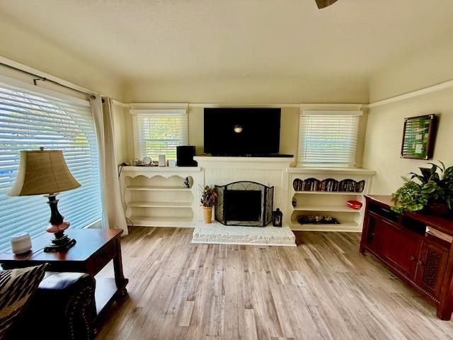 living room featuring a brick fireplace and light wood-type flooring