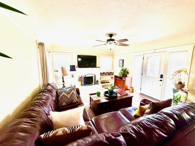 living room with ceiling fan and a textured ceiling