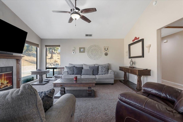 living room featuring a tiled fireplace, vaulted ceiling, carpet flooring, and ceiling fan