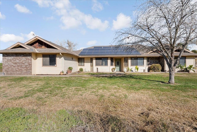 ranch-style house featuring a front lawn and solar panels