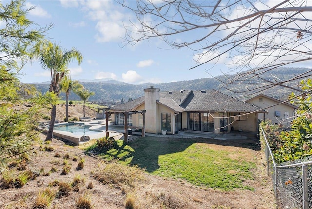 back of house featuring a mountain view, a patio area, and a lawn